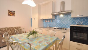A modern kitchen with a dining table, chairs, a stove, and a gas range. - Appartamento a Capaccio ID 3338 (Licinella-Torre di Paestum)