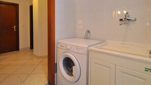 A laundry room with a washing machine, a sink, and a door. - Appartamento a Capaccio ID 3338 (Licinella-Torre di Paestum)