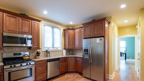 A modern kitchen with wooden cabinets, stainless steel appliances, and a large window providing natural light. - Roscoe Village- Only steps to cute shops & dining! Sleeps 4-6 (Chicago)