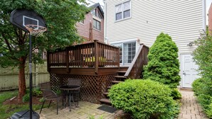 A backyard with a basketball hoop, a wooden deck, a staircase, and a small patio area with chairs. - Roscoe Village- Only steps to cute shops & dining! Sleeps 4-6 (Chicago)