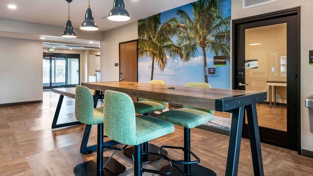 Una sala de conferencias con una mesa de madera, sillas tapizadas en verde e iluminación colgante.