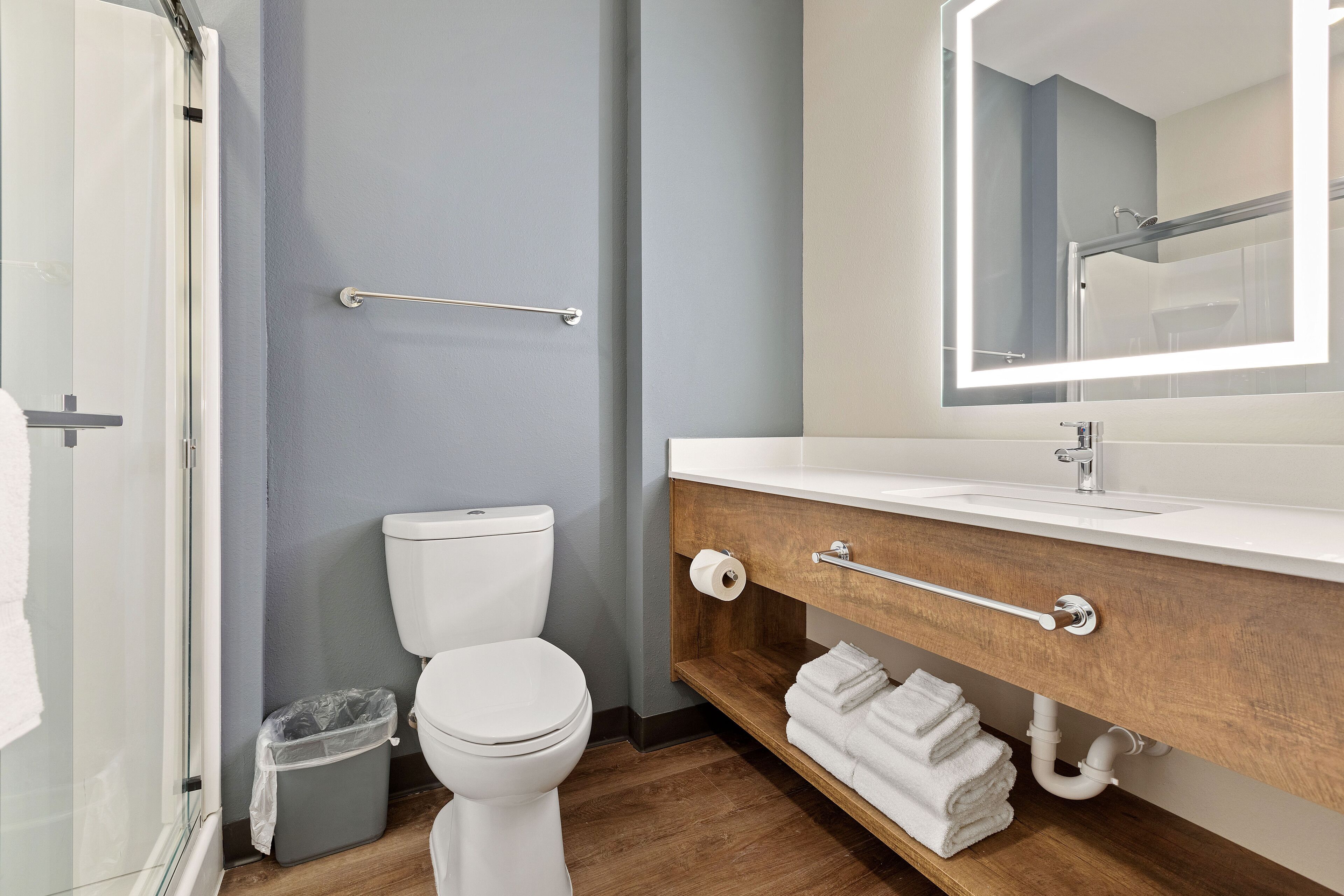 Un baño moderno con inodoro, lavamanos y espejo.