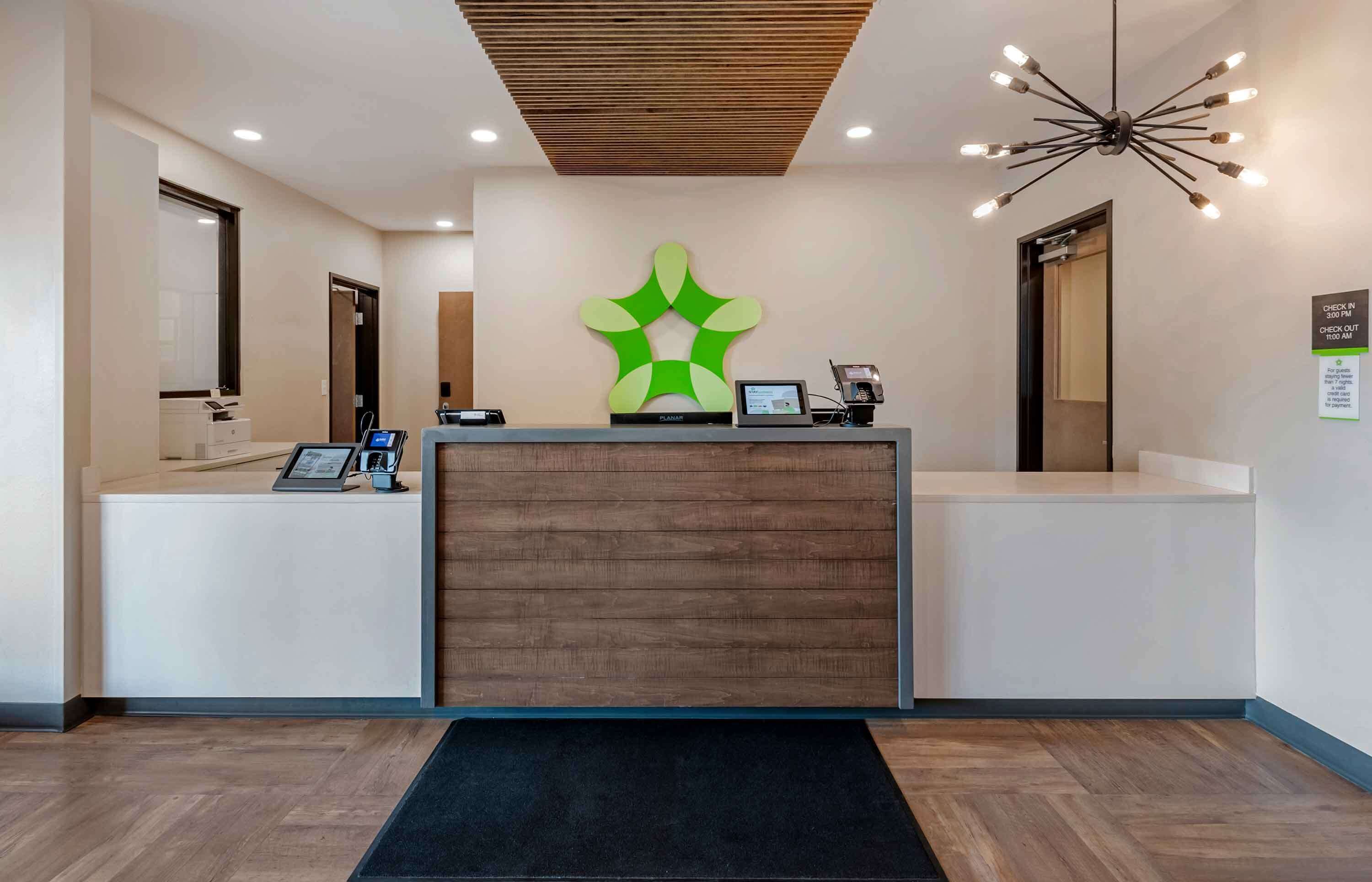 A reception desk with a modern design, a digital display, and a unique green wall art piece.