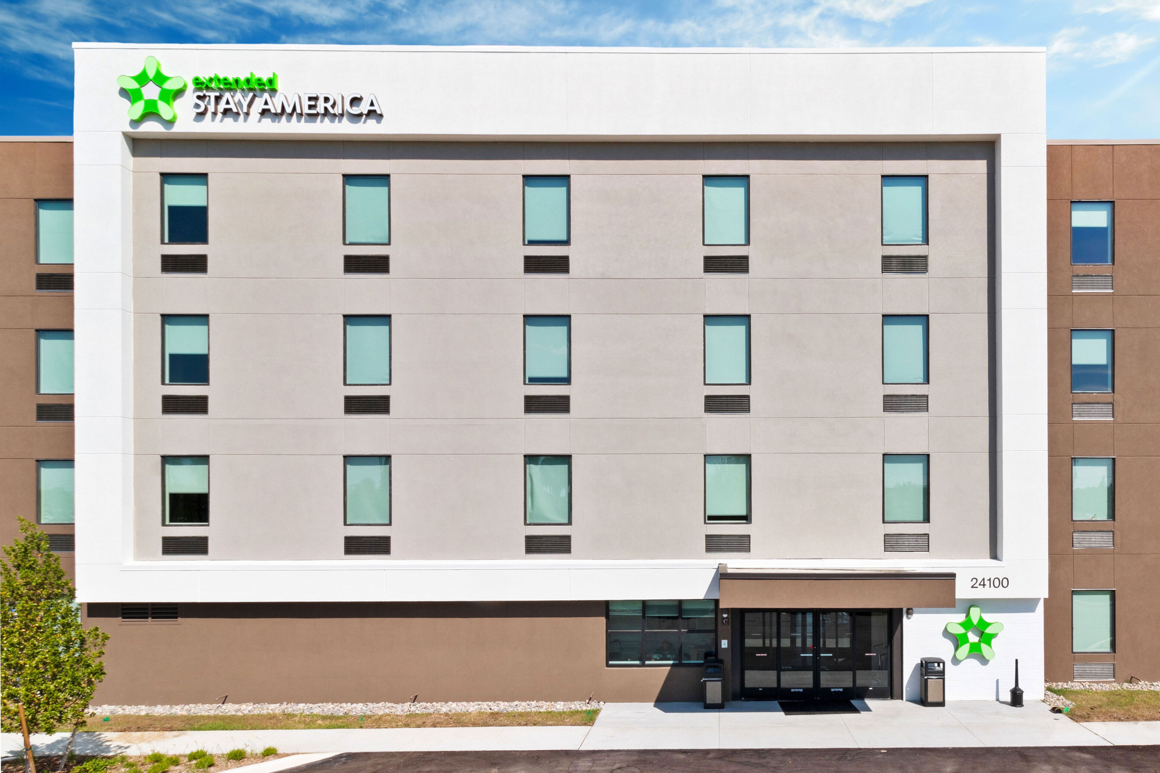 A modern hotel building with a sign reading "Extended Stay America" and the number 24100.