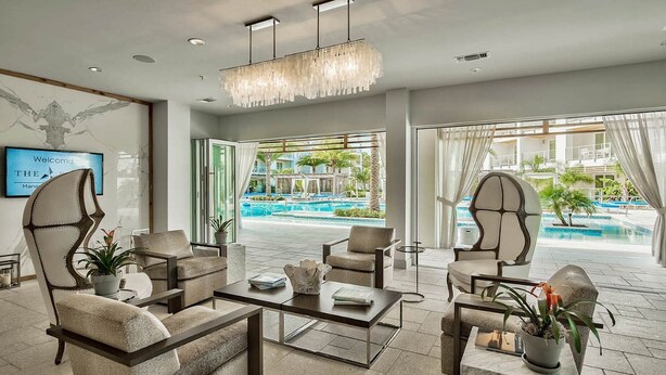 A modern lobby with a pool view, featuring a sofa set, a coffee table, and a chandelier. - The Pointe by 360 Blue (Panama City Beach)