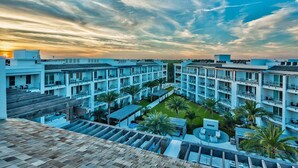 A multi-story hotel with a rooftop terrace, balconies, and a courtyard with palm trees. - The Pointe by 360 Blue (Panama City Beach)