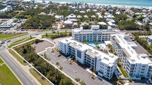 A modern hotel with multiple buildings, a parking lot, and a view of the ocean. - The Pointe by 360 Blue (Panama City Beach)