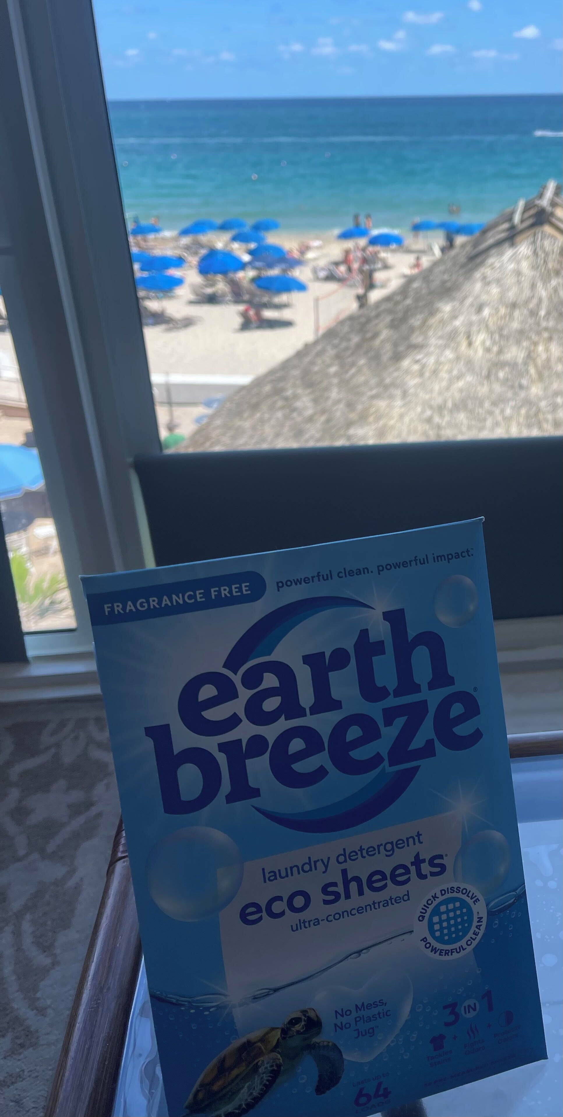A package of Earth Breeze laundry detergent sheets in front of a window with a beach view.
