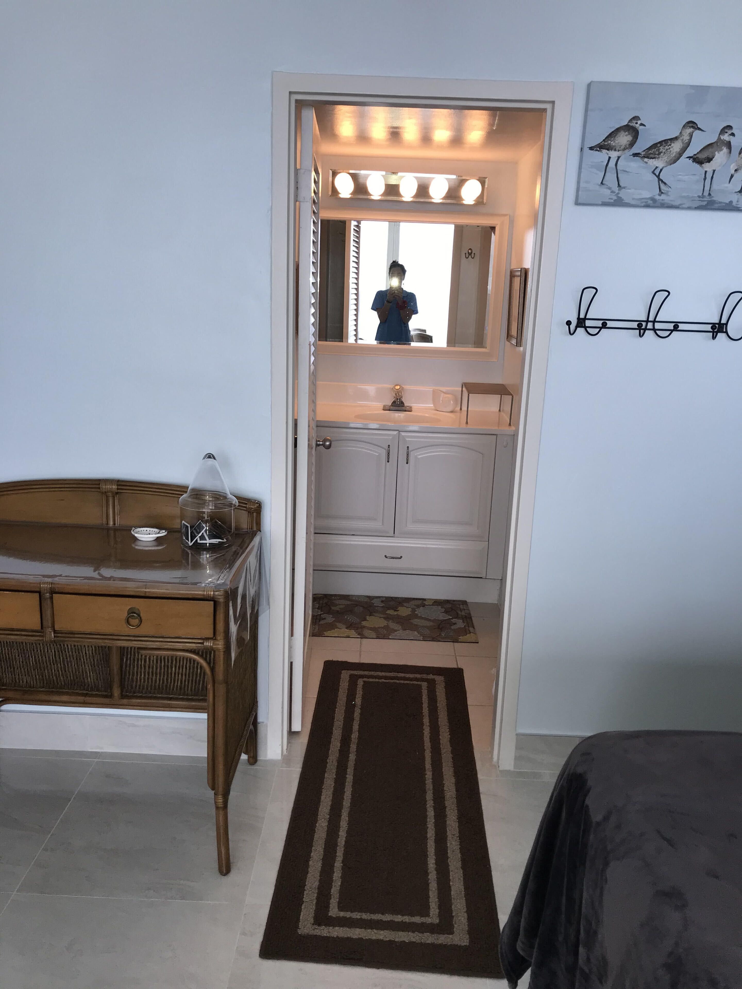 Et soveværelse med et toiletbord, en kommode, et spejl og en seng.