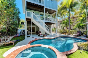 A two-story house with a swimming pool, outdoor seating, and a staircase leading to the upper level. - Hop, Skip and a Beach - 4Bed Pool Home in Anna Maria City - By Island Real Estat (Anna Maria)