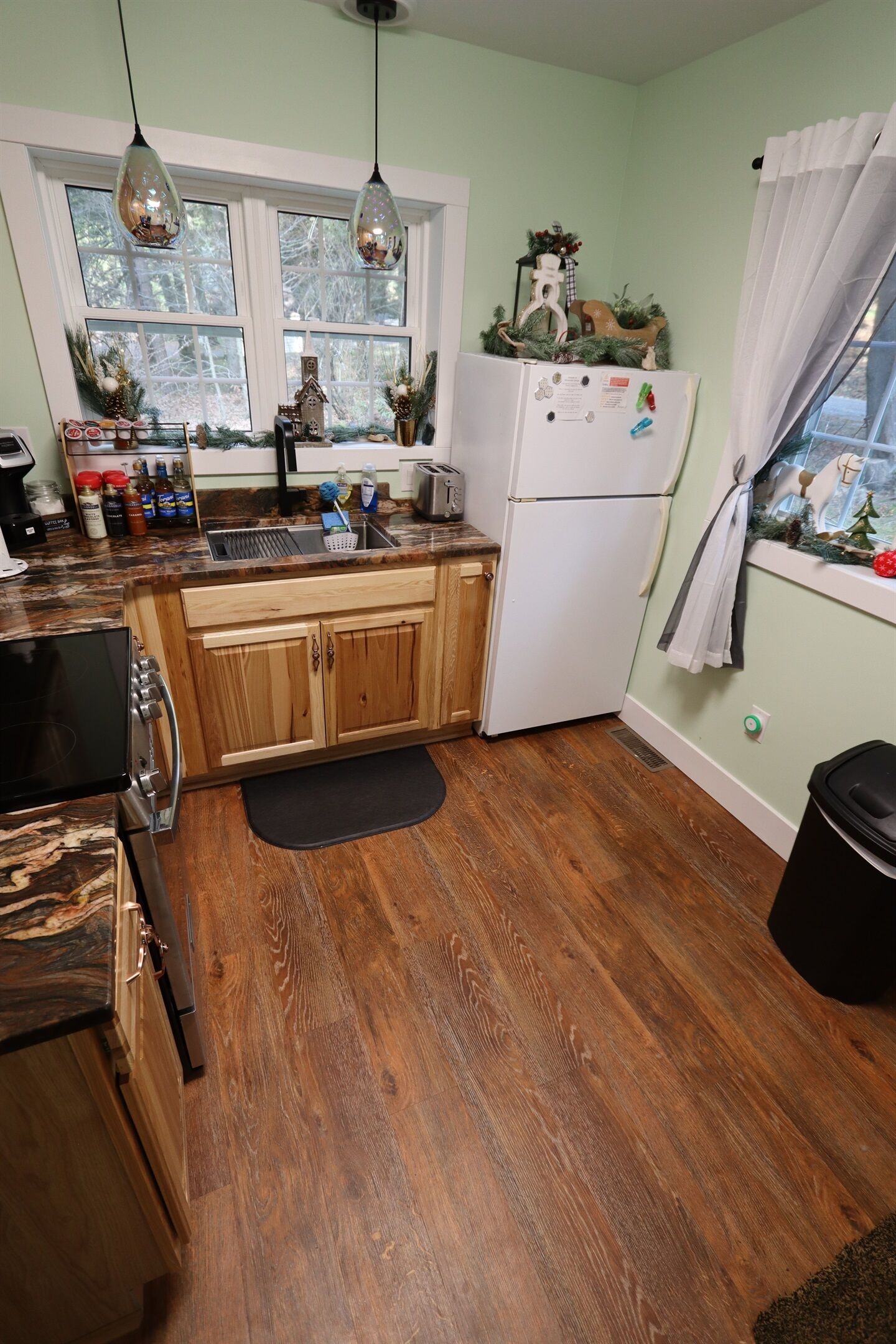 A kitchen with wooden cabinets, a white refrigerator, and a window with a view of trees.