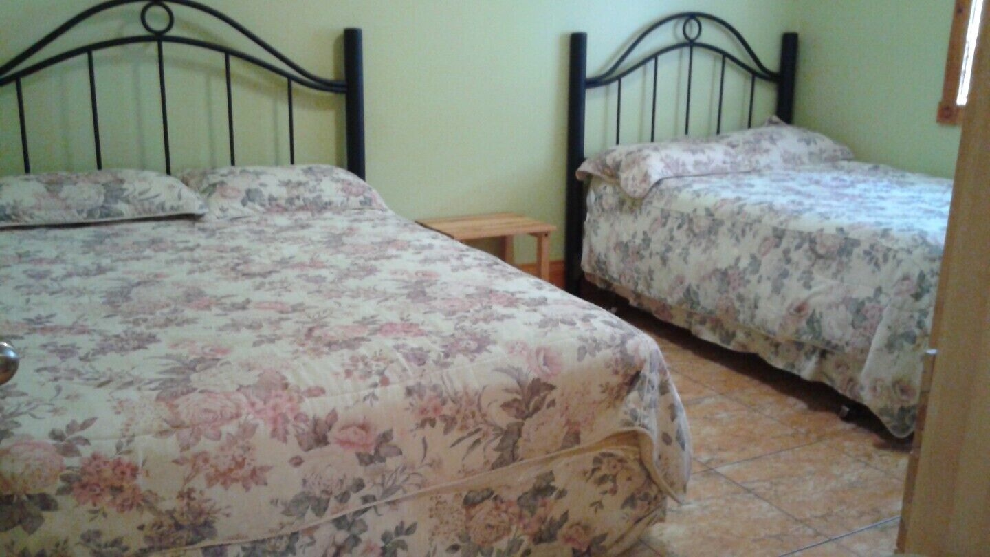 A bedroom with two beds, each with floral bedding, a wooden nightstand, and a metal headboard.