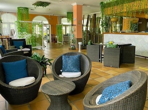 A lobby with wicker furniture, a reception desk, and green plants. - Albaida Nature (Moguer)