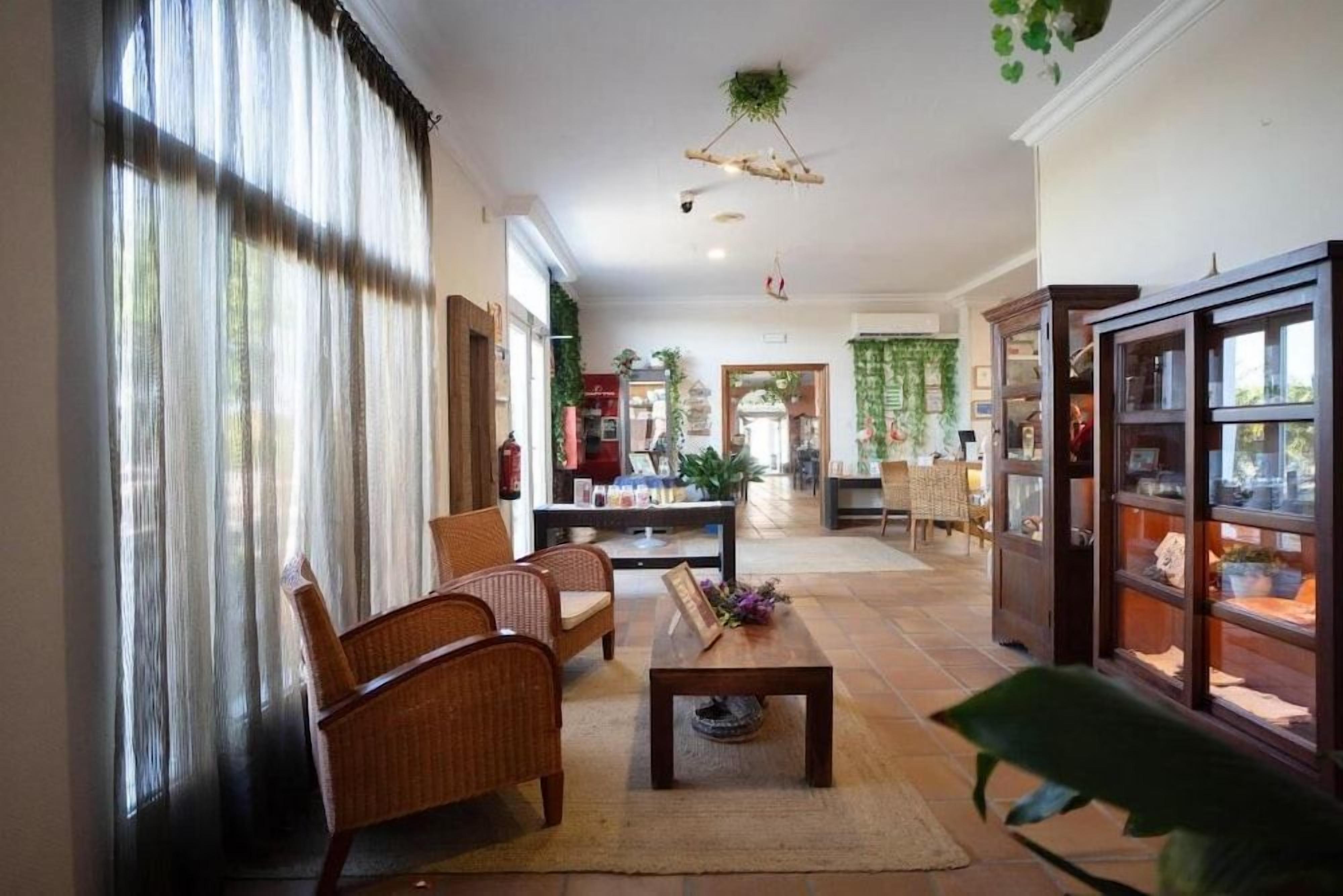 Amplia sala de estar con mobiliario de mimbre, una mesa de centro y una estantería.
