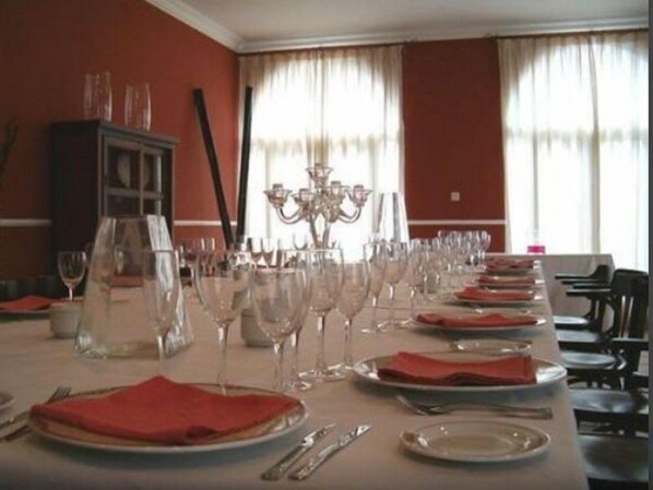 A dining room with multiple tables set for a meal, each with plates, cutlery, and wine glasses.