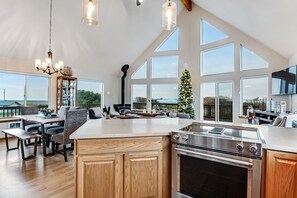 A spacious kitchen with a large island, wooden cabinets, and a stainless steel stove.