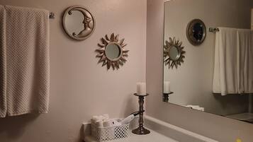 A bathroom with a sink, mirror, towel rack, decorative wall mirrors, and a candle.