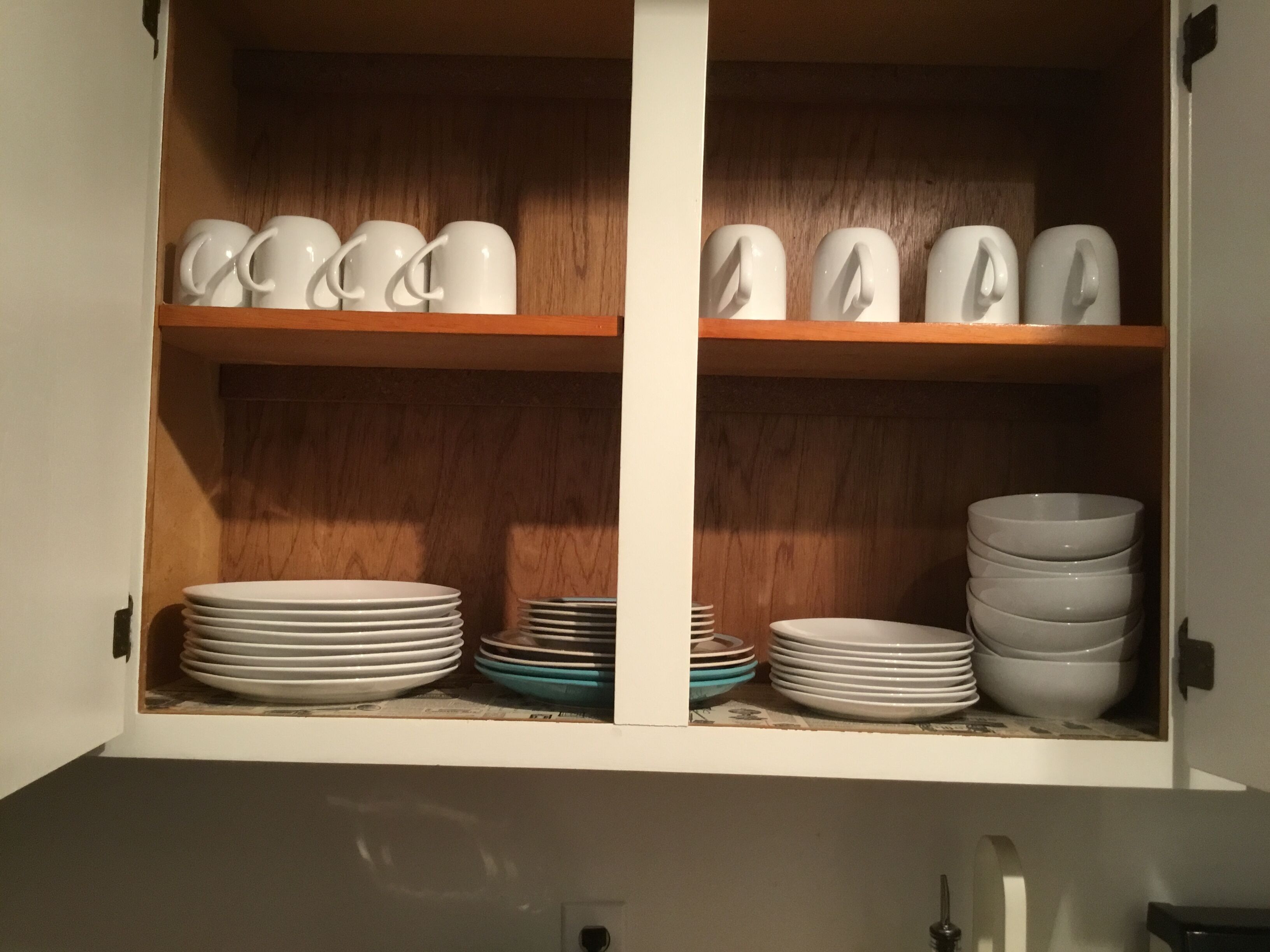 Un armari de cuina amb tasses i plats blancs.