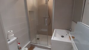 Une salle de bain moderne avec une douche à parois de verre, des toilettes blanches et un lavabo.