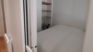 Une chambre à coucher avec un lit, une porte blanche et une petite fenêtre.