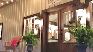 Un edificio de estilo rústico tipo granero, con un letrero atractivo, vigas de madera y plantas en macetas.