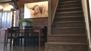 Un salón amplio con una escalera de madera, una mesa de comedor con sillas y un mural grande en la pared.