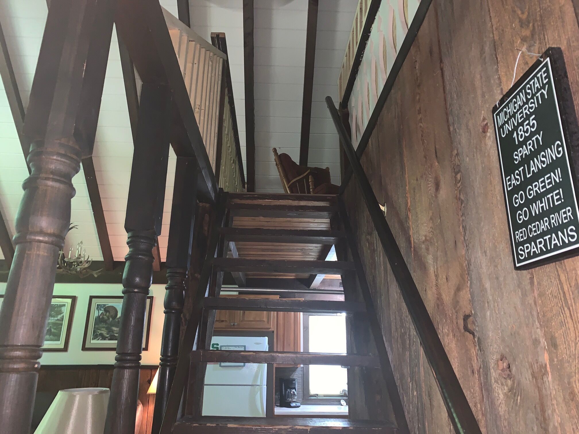 A wooden staircase with a sign on the wall.