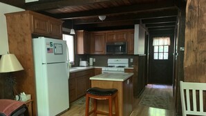 Una cocina con armarios de madera, un refrigerador, una estufa y un microondas.