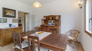 Un comedor con una mesa de madera, sillas, un cuenco de fruta y una lámpara colgante.