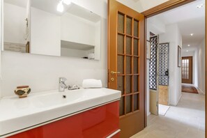 A bathroom with a white sink, red cabinet, and a wooden door with glass panels. - GuestHost - Charming and bright flat for 5 people in Cernobbio, in the hamlet of Rovenna, on the way up to mount Bisbino.The apartment, furnished with vintage and modern furniture, comes with private parking and enjoyable outdoor spaces, like the pergola (Cernobbio)