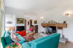 A living room with teal sofas, a red cabinet, a TV, and a fireplace.