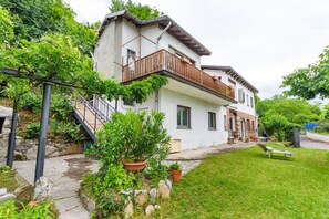 A two-story house with a balcony, stone steps, and a garden. - GuestHost - Charming and bright flat for 5 people in Cernobbio, in the hamlet of Rovenna, on the way up to mount Bisbino.The apartment, furnished with vintage and modern furniture, comes with private parking and enjoyable outdoor spaces, like the pergola (Cernobbio)