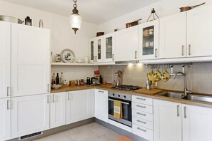 A kitchen with white cabinets, a stove, a sink, and a hanging pot rack.