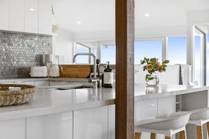 A modern kitchen with a central island, a built-in sink, and a view to the outside.