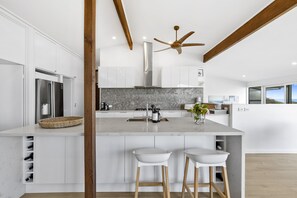 A modern kitchen with white cabinetry, a hexagonal backsplash, and a central island with stools.