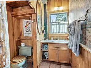 Et badeværelse i en træhytte med toilet, vask og håndklædetørrestativ.