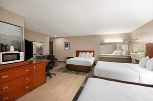 Habitación de hotel con cama, escritorio con computadora, microondas y televisión.