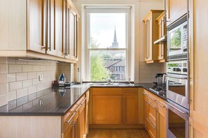 A modern kitchen with wooden cabinets, a black countertop, and stainless steel appliances.