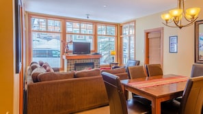 A cozy living room with a fireplace, comfortable seating, and a dining area. - Settlers Crossing #61 by Bear Country (Sun Peaks)