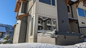 A multi-story building with a snow-covered roof and a ski lift attached to the side. - Echo Landing #12 by Bear Country (Sun Peaks)
