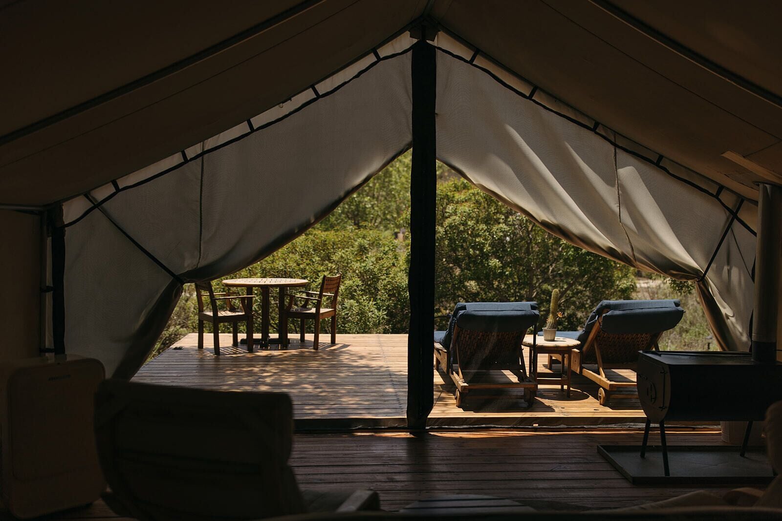 A tent with a wooden deck, a table, and chairs.