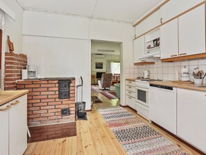 Una cocina con pared de ladrillo, armarios blancos, estufa y lavavajillas.