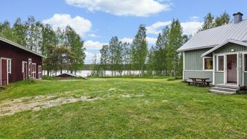 A grassy area with two buildings, one red and one green, near a body of water.
