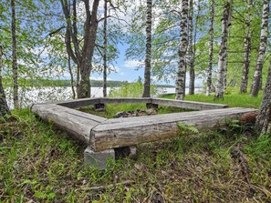 Un brasero de madera rodeado de árboles y un lago.