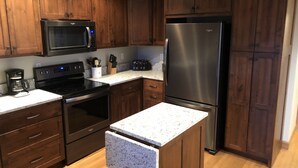 A modern kitchen with dark wooden cabinets, stainless steel appliances, a granite countertop, and a built-in oven. - Table Rock Lake, Steps to Marina (Holiday Island)