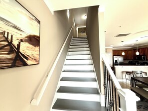 Una escalera que lleva a un cuarto de lavado, con un área de cocina visible en la parte superior.