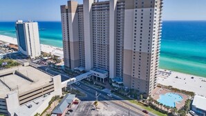 A high-rise hotel with multiple floors, a swimming pool, and a beach view.