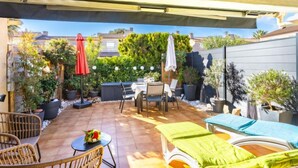 Un espace patio aménagé avec du mobilier d’extérieur, une table et des plantes en pot.