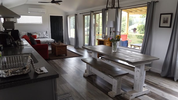 A spacious living area with a wooden bench, a dining table, and a kitchen area with a sink and stove.