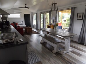 A spacious living area with a wooden bench, a dining table, and a kitchen area with a sink and stove. - The Ranch in Mt Airy (Mount Airy)